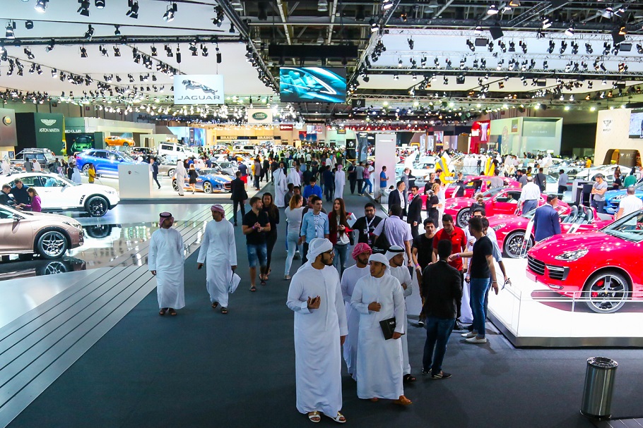 Visitors walking through a Dubai International Motor Show floor.