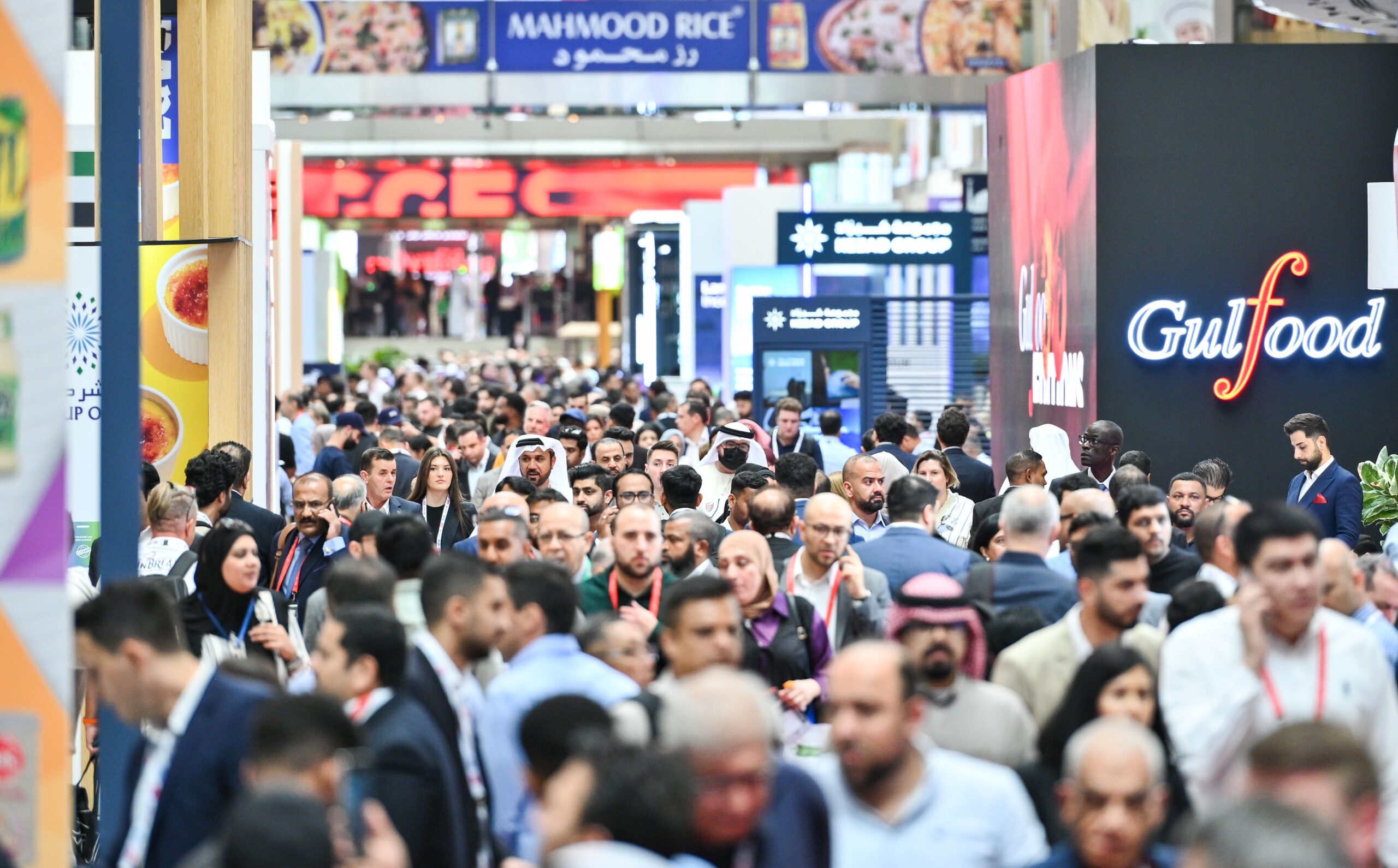 A busy Gulfood exhibition aisle filled with visitors and international food trade stands.