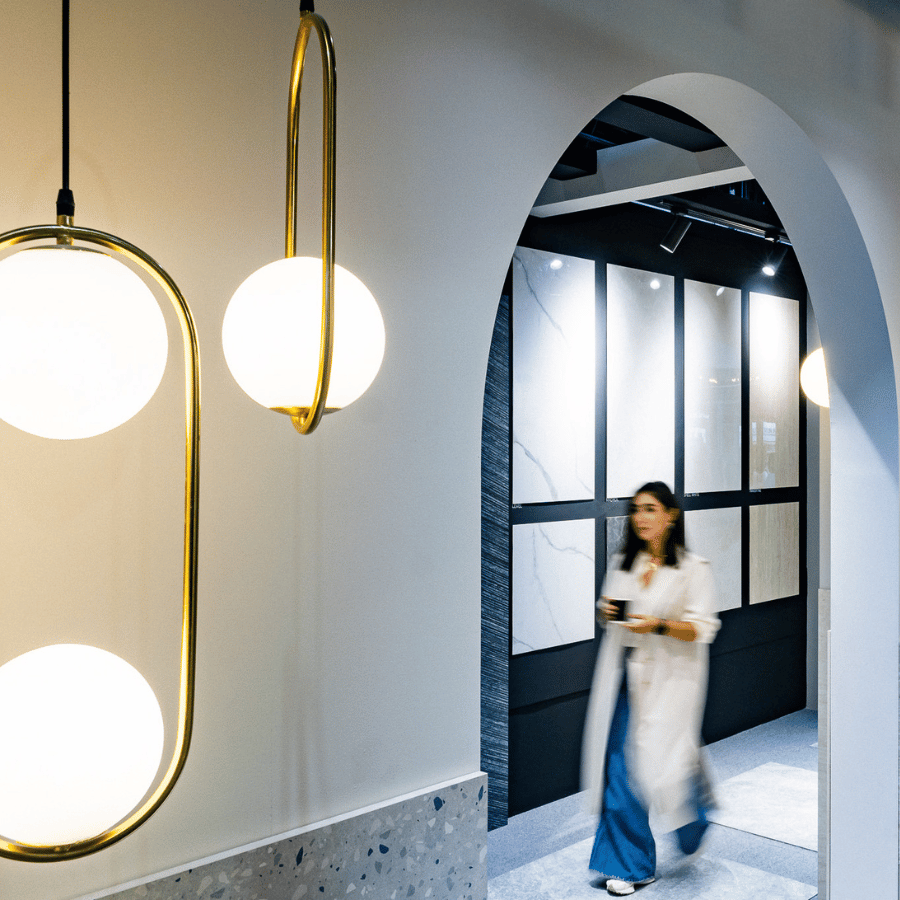 A visitor walking through an interior-products installation with pendant lights and display structures.